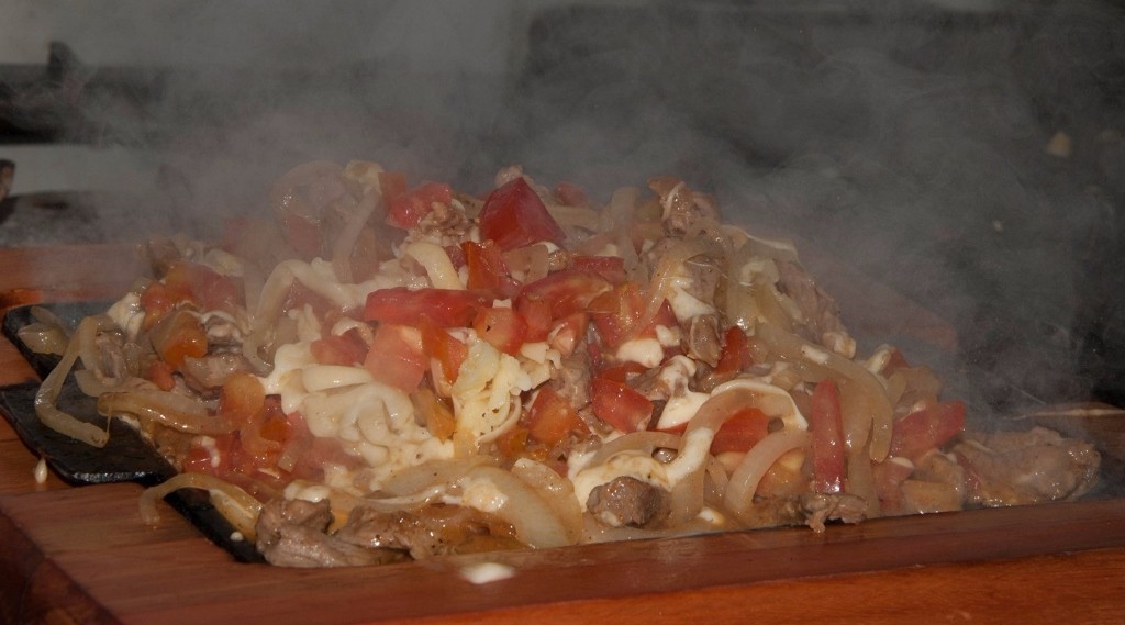 Porção Santo Agostinho, feita com 400 gramas de contra-filé em tiras, cebola, tomate, especiarias e muçarela